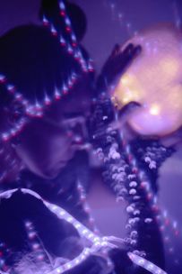 Woman holding a glowing orb surrounded by LED lights in a creative, mystical setting.